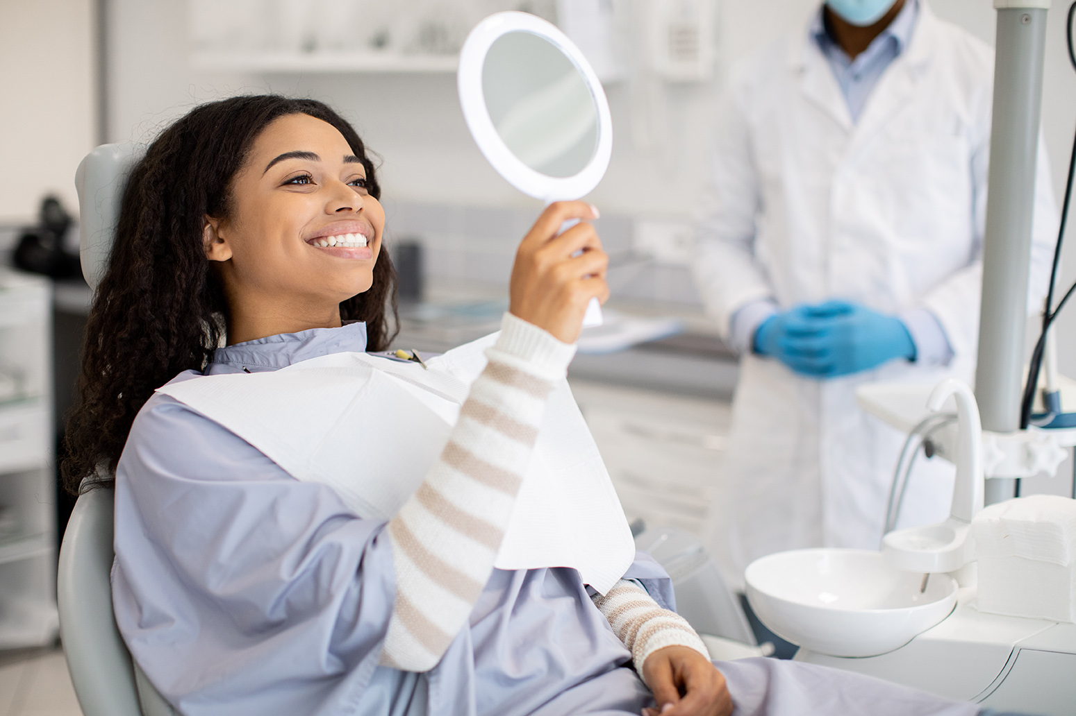 woman looking into a mirror during cosmetic dental appointment at medford main dental pc