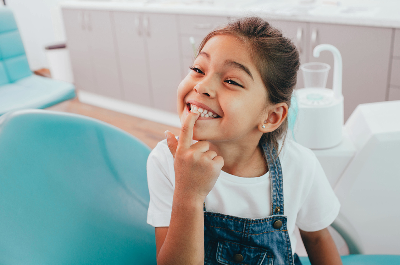 pediatric dental patient pointing to her tooth during family dental care appointment in Medford, MA