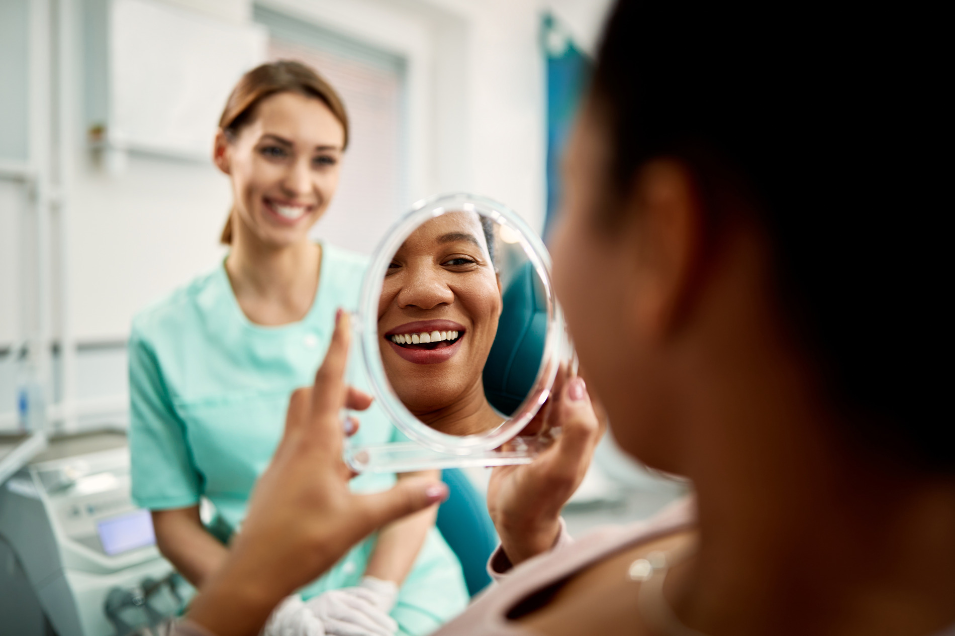 Woman looking at her clean teeth after her regular cleaning appointment at Medford Main Street Dental