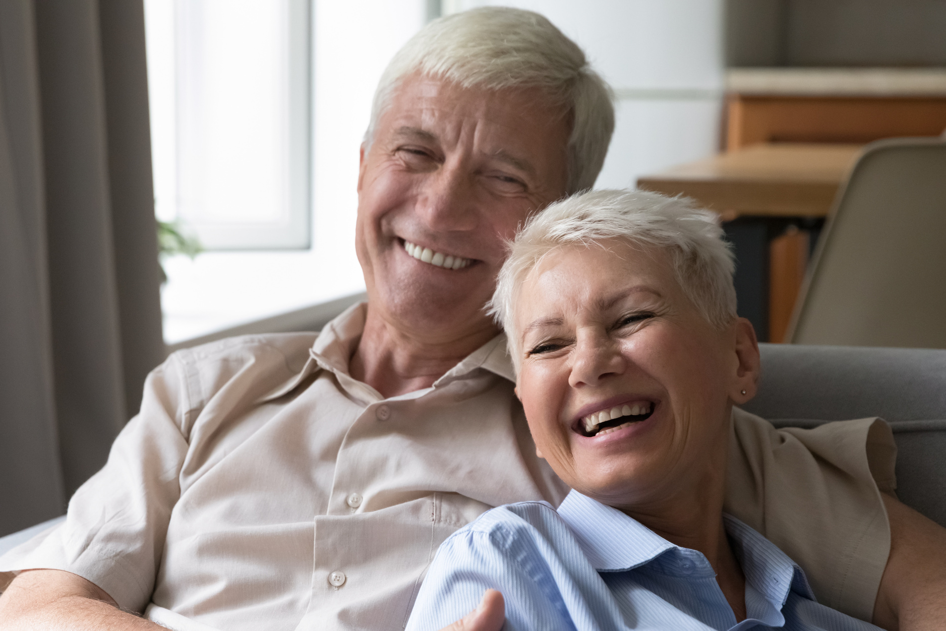 Couple lounge on the couch with their new custom dentures from Dr. Do at Medford Main Street Dental