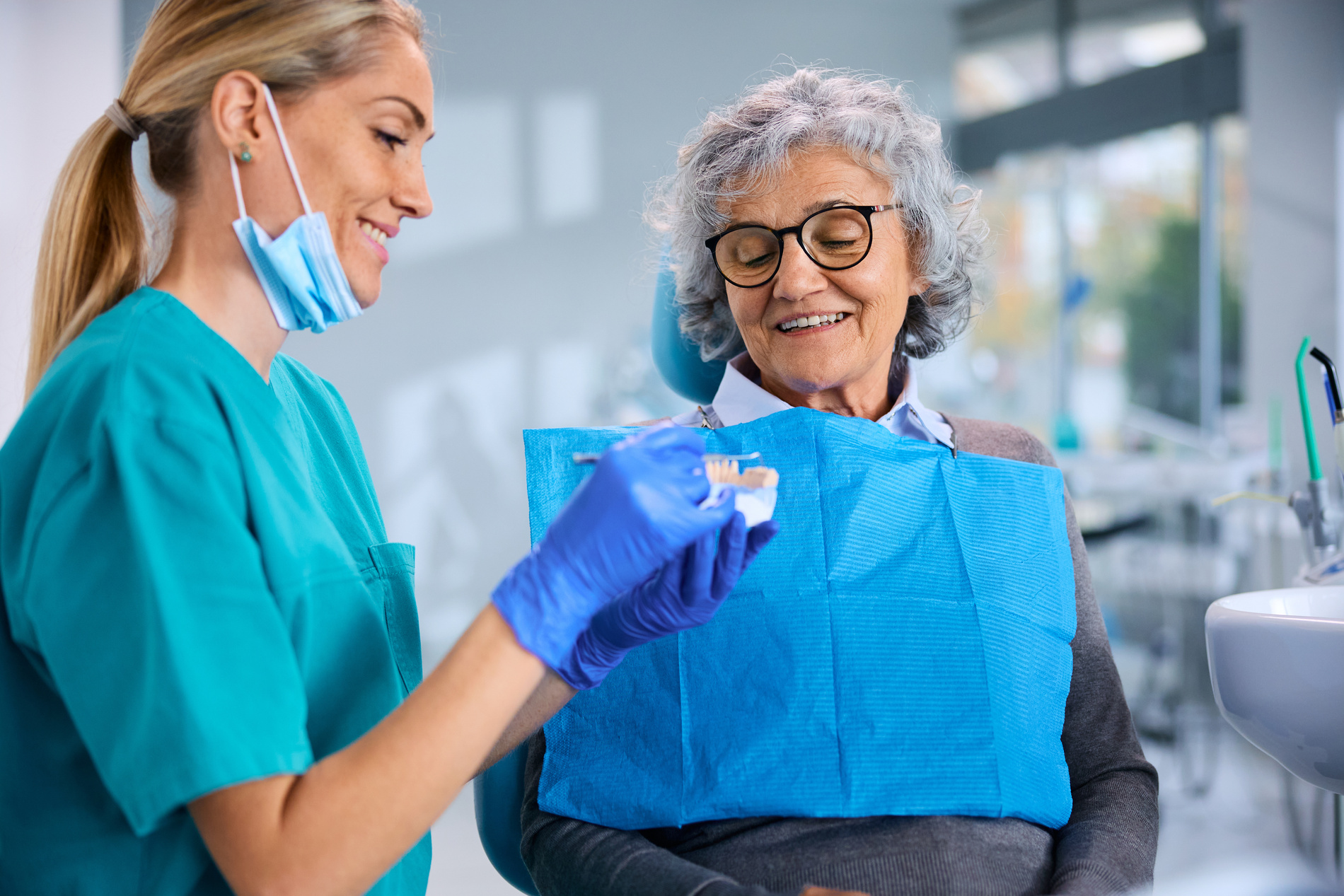 Dentist shows older lady her new full dentures in Medford MA
